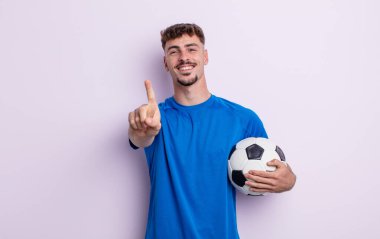 Genç yakışıklı adam gururla gülümsüyor ve kendinden emin bir numara oluyor. futbol kavramı
