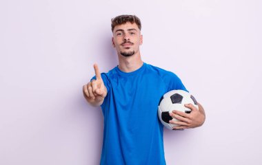 Genç yakışıklı adam gülümsüyor ve arkadaş canlısı görünüyor, bir numarayı gösteriyor. futbol kavramı