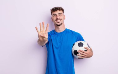 Genç yakışıklı adam gülümsüyor ve arkadaş canlısı görünüyor, dört numarayı gösteriyor. futbol kavramı