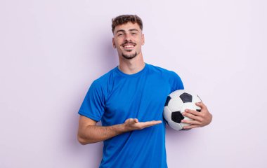Genç yakışıklı adam neşeyle gülümsüyor, mutlu hissediyor ve bir konsept gösteriyor. futbol kavramı