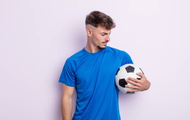 Genç ve yakışıklı bir adam üzgün, üzgün ya da kızgın hissediyor ve yan tarafa bakıyor. futbol kavramı
