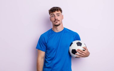 Kafası karışmış ve kafası karışmış genç yakışıklı bir adam. futbol kavramı