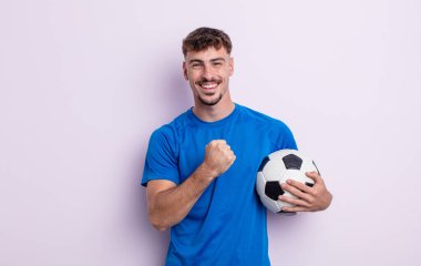 Genç yakışıklı adam kendini mutlu hissediyor ve bir meydan okumayla yüzleşiyor ya da kutluyor. futbol kavramı