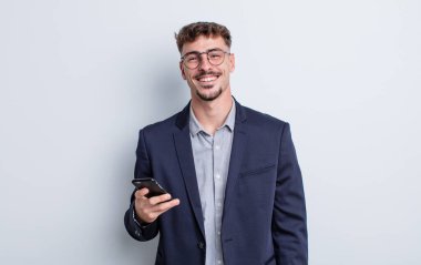 Genç yakışıklı adam mutlu bir şekilde gülümsüyor, eli kalçasında ve kendinden emin. iş kavramı