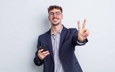 Genç yakışıklı adam gülümsüyor ve mutlu görünüyor, zafer ya da barış işareti yapıyor. iş kavramı