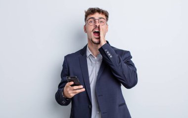 Genç yakışıklı adam mutlu hissediyor, elleri ağzının kenarında bağırıyor. iş kavramı