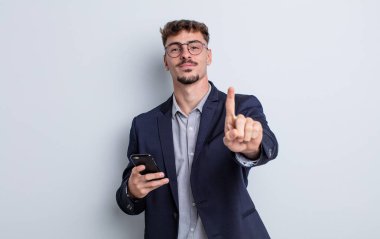 young handsome man smiling proudly and confidently making number one. business concept