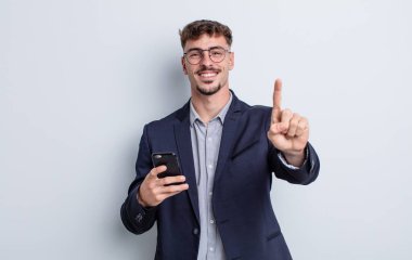 young handsome man smiling and looking friendly, showing number one. business concept