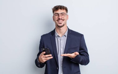young handsome man smiling cheerfully, feeling happy and showing a concept. business concept