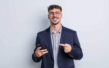 young handsome man smiling cheerfully, feeling happy and pointing to the side. business concept