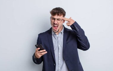 Genç yakışıklı adam mutsuz ve stresli görünüyor, intihar jesti silah işareti yapıyor. iş kavramı