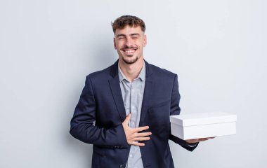 Genç yakışıklı bir adam komik bir şakaya yüksek sesle gülüyor. beyaz kutu paketi