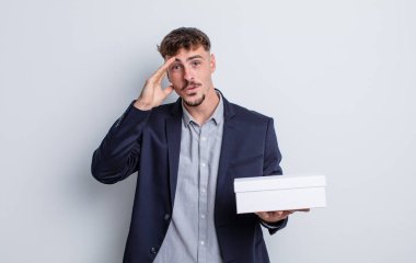 Genç yakışıklı adam mutlu, şaşkın ve şaşırmış görünüyor. beyaz kutu paketi