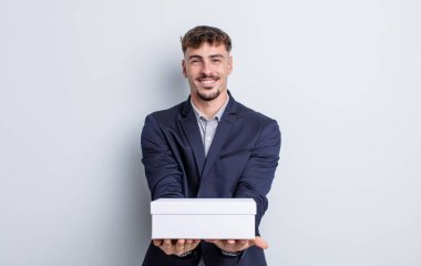 Genç ve yakışıklı bir adam arkadaşça gülümsüyor ve bir konsept sunuyor. beyaz kutu paketi
