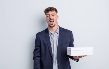 Genç, yakışıklı, neşeli ve asi tavırlı, şaka yapan ve dilini dışarı çıkaran bir adam. beyaz kutu paketi