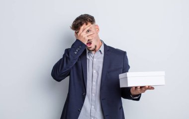 Genç, yakışıklı adam şok olmuş, korkmuş ya da korkmuş görünüyor. beyaz kutu paketi