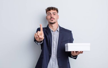 Genç yakışıklı adam gururla gülümsüyor ve kendinden emin bir numara oluyor. beyaz kutu paketi