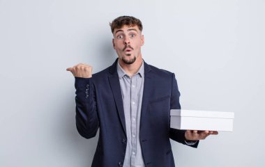 İnanamadığı için şaşırmış genç ve yakışıklı bir adam. beyaz kutu paketi