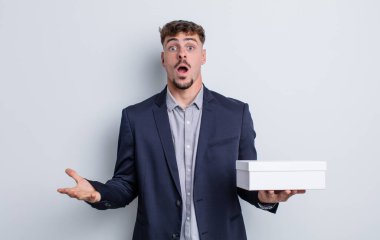 Genç yakışıklı adam, inanılmaz bir sürprizle şaşkına dönmüş ve hayrete düşmüştü. beyaz kutu paketi