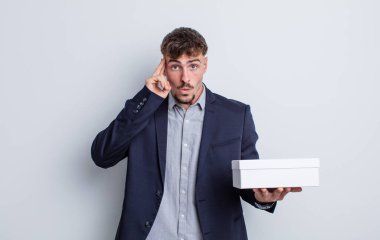 Genç yakışıklı adam şaşırmış görünüyor, yeni bir düşünce, fikir ya da konsept fark ediyor. beyaz kutu paketi