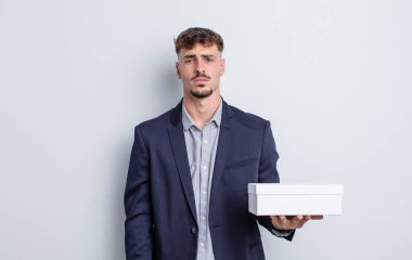 Genç ve yakışıklı bir adam üzgün ve mızmızlanıyor. Mutsuz bir bakışı var ve ağlıyor. beyaz kutu paketi