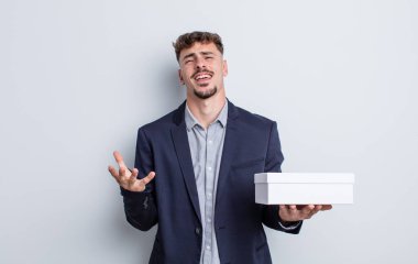 Genç yakışıklı adam umutsuz, sinirli ve stresli görünüyor. beyaz kutu paketi