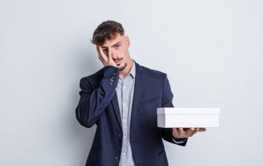 Genç yakışıklı bir adam bıkkın, hayal kırıklığına uğramış ve yorucu bir geceden sonra uykulu hissediyor. beyaz kutu paketi