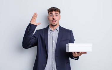 Genç yakışıklı adam ellerini havaya kaldırarak çığlık atıyor. beyaz kutu paketi