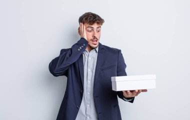 Genç yakışıklı adam mutlu, heyecanlı ve şaşırmış hissediyor. beyaz kutu paketi