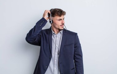 Kafası karışmış, kafası karışmış, kaşınan genç, yakışıklı bir adam. tele pazarlamacı kavramı