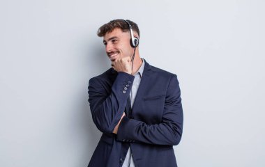 Genç ve yakışıklı bir adam mutlu ve kendinden emin bir ifadeyle gülümsüyor, elleri çenesinde. tele pazarlamacı kavramı