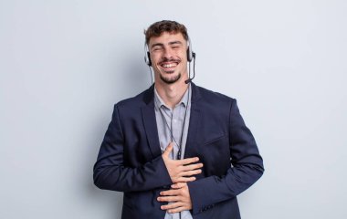 Genç yakışıklı bir adam komik bir şakaya yüksek sesle gülüyor. tele pazarlamacı kavramı