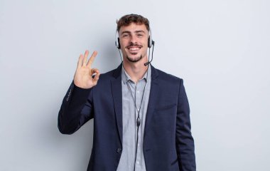 Genç yakışıklı adam kendini mutlu hissediyor, iyi bir jestle onaylıyor. tele pazarlamacı kavramı