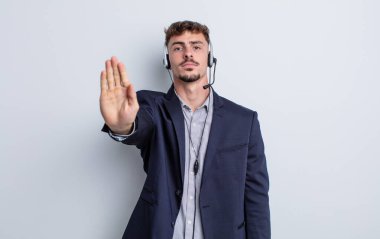 Genç ve yakışıklı adam ciddi görünüyor. Avuç içi gösteriyor. Durdurma hareketi yapıyor. tele pazarlamacı kavramı