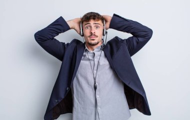 Genç ve yakışıklı bir adam stresli, endişeli ya da korkmuş hissediyor. Elleri başının üstünde. tele pazarlamacı kavramı