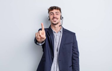 Genç yakışıklı adam gururla gülümsüyor ve kendinden emin bir numara oluyor. tele pazarlamacı kavramı