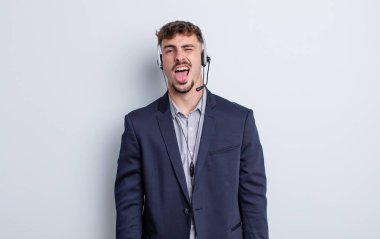 Genç, yakışıklı, neşeli ve asi tavırlı, şaka yapan ve dilini dışarı çıkaran bir adam. tele pazarlamacı kavramı