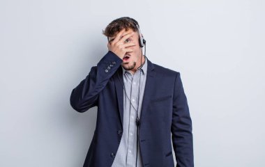 Genç, yakışıklı adam şok olmuş, korkmuş ya da korkmuş görünüyor. tele pazarlamacı kavramı