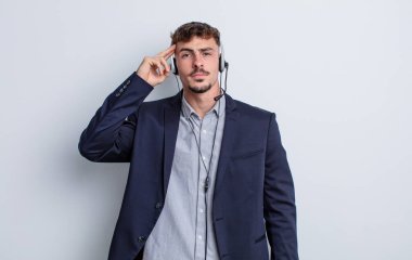 Genç yakışıklı adam kafası karışık ve şaşkın hissediyor, deli olduğunu gösteriyor. tele pazarlamacı kavramı