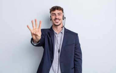 Genç yakışıklı adam gülümsüyor ve arkadaş canlısı görünüyor, dört numarayı gösteriyor. tele pazarlamacı kavramı