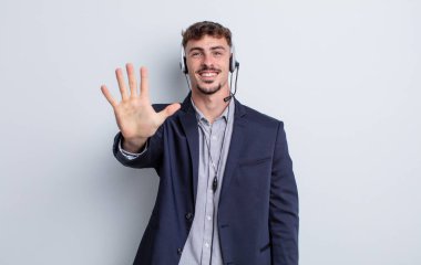 Genç yakışıklı adam gülümsüyor ve arkadaş canlısı görünüyor, beş numarayı gösteriyor. tele pazarlamacı kavramı