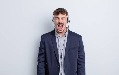 Genç yakışıklı adam agresif bir şekilde bağırıyor, çok kızgın görünüyor. tele pazarlamacı kavramı