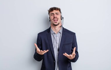 Genç yakışıklı adam umutsuz, sinirli ve stresli görünüyor. tele pazarlamacı kavramı