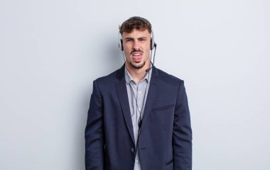 Genç ve yakışıklı bir adam tiksinmiş ve sinirlenmiş hissediyor ve dilini dışarı çıkarıyor. tele pazarlamacı kavramı