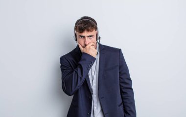 Ağzı ve gözleri açık ve eli çenesinde genç yakışıklı bir adam. tele pazarlamacı kavramı