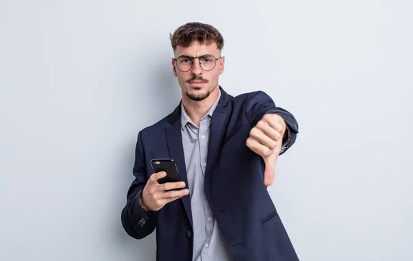 Jovem Bonito Homem Sentindo Cruz Mostrando Polegares Para Baixo Conceito — Fotografia de Stock