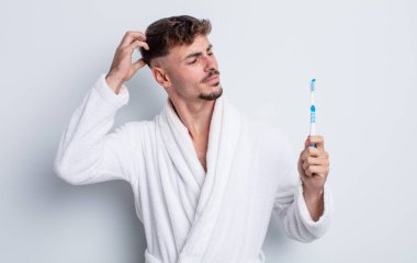 Kafası karışmış, kafası karışmış, kaşınan genç, yakışıklı bir adam. diş fırçası kavramı