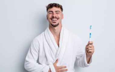 Genç yakışıklı bir adam komik bir şakaya yüksek sesle gülüyor. diş fırçası kavramı