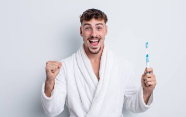 Genç yakışıklı adam şok olmuş hissediyor, gülüyor ve başarıyı kutluyor. diş fırçası kavramı