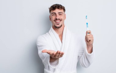 Genç ve yakışıklı bir adam arkadaşça gülümsüyor ve bir konsept sunuyor. diş fırçası kavramı